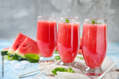 Glasses with fresh watermelon smoothie on color table