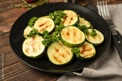 Plate with tasty grilled zucchini on wooden table