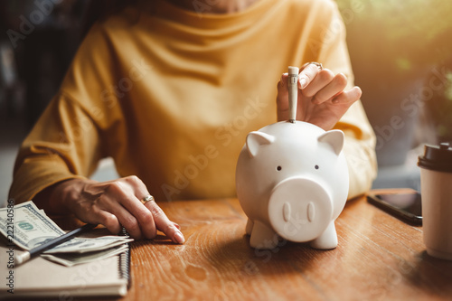 woman hand putting money bank note dollar into piggy for saving money wealth and financial concept. photo