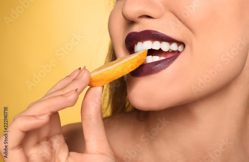 Beautiful young woman with dark lipstick and lemon slice on color background  closeup