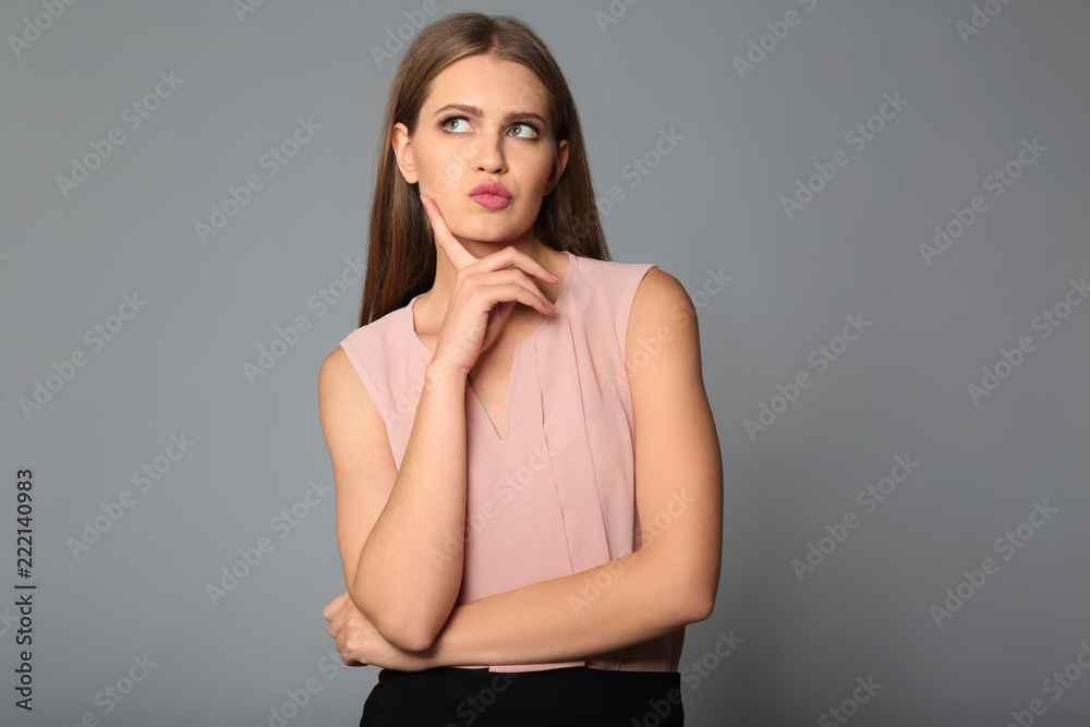 Thoughtful young businesswoman on grey background Thoughtful young businesswoman on grey background
