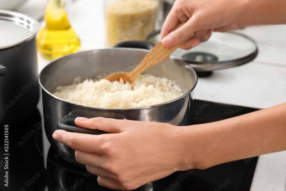 Woman cooking rice on stove in kitchen, closeup Woman cooking rice on stove in kitchen, closeup
