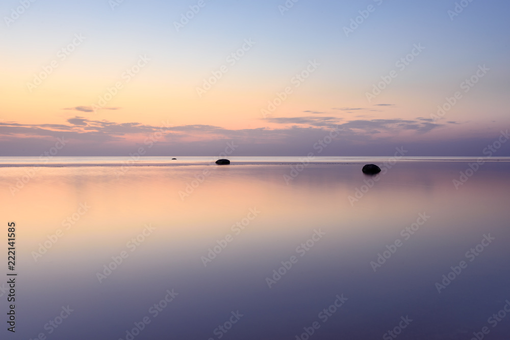 The sky is reflected in the sea at sunset on a long exposure.