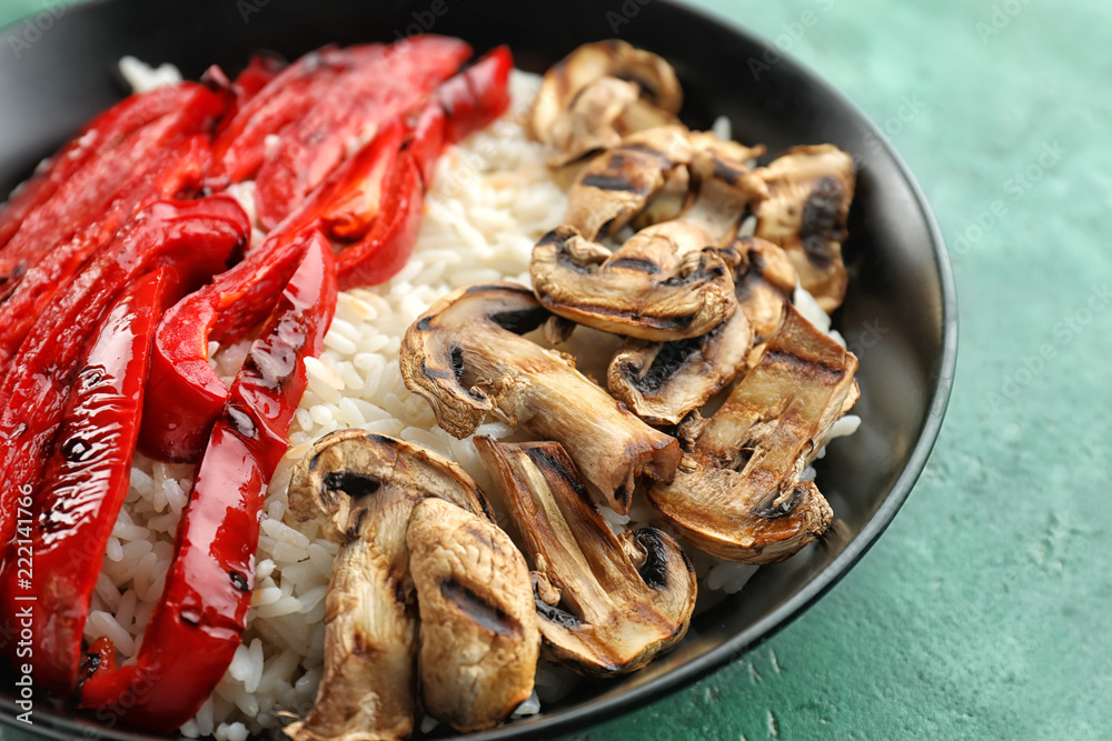 Plate with tasty boiled rice, pepper and mushrooms on color table