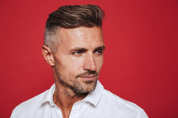 Portrait closeup of adult man 30s in white shirt looking aside, isolated over red background