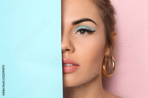 Beautiful young woman with pink lipstick and blank poster on color background