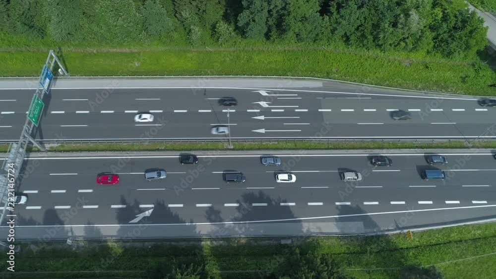 AERIAL, TOP DOWN: Colorful vehicles move along the busy freeway and under a concrete overpass. Flying above cars and trucks driving up and down a bustling highway running through the green nature. AERIAL, TOP DOWN: Colorful vehicles move along the busy freeway and under a concrete overpass. Flying above cars and trucks driving up and down a bustling highway running through the green nature.