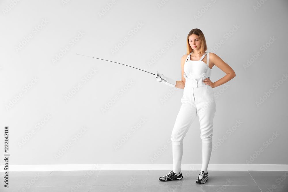 Young female fencer near light wall Young female fencer near light wall