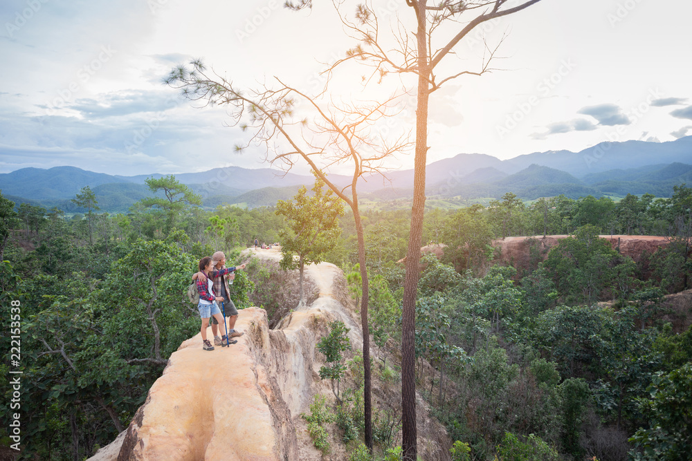 Hikers in Pai Canyon resting enjoying view Hiking couple in beautiful nature landscape with hoodoos, pinnacles and spires rock formations. Pai Canyon in Huai Nam Dang National Park, Thailand.