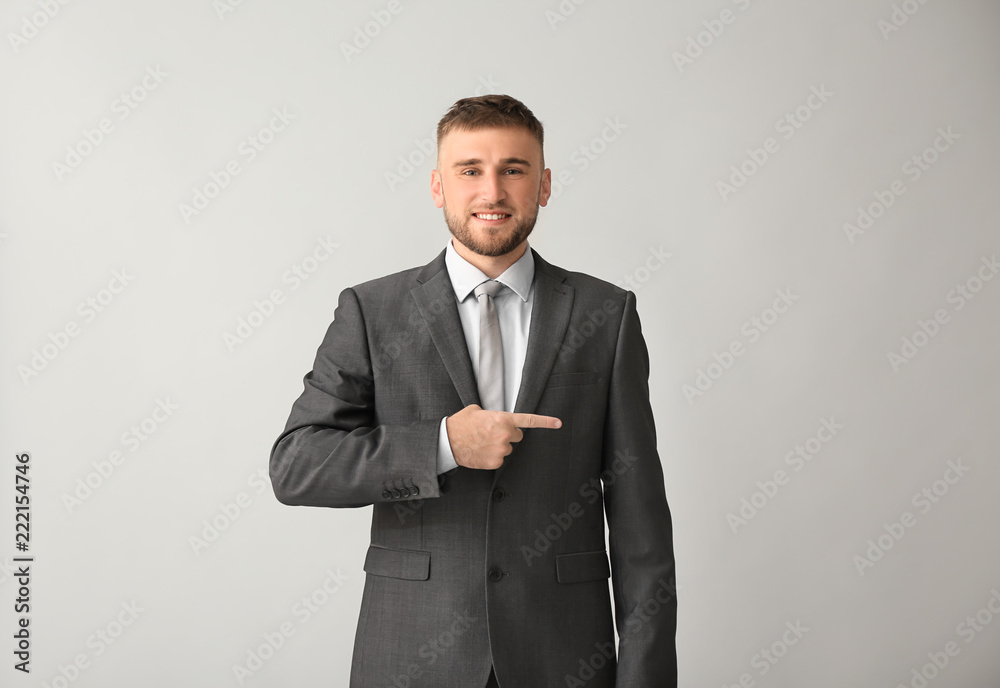 Handsome businessman pointing at something on grey background Handsome businessman pointing at something on grey background