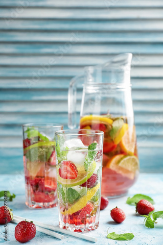 Glassware of fresh strawberry lemonade on color table