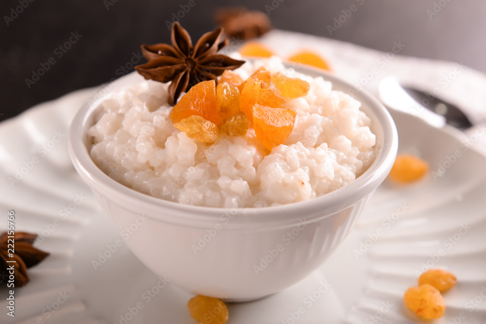 Delicious rice pudding with dried fruits and anise in bowl on plate Delicious rice pudding with dried fruits and anise in bowl on plate