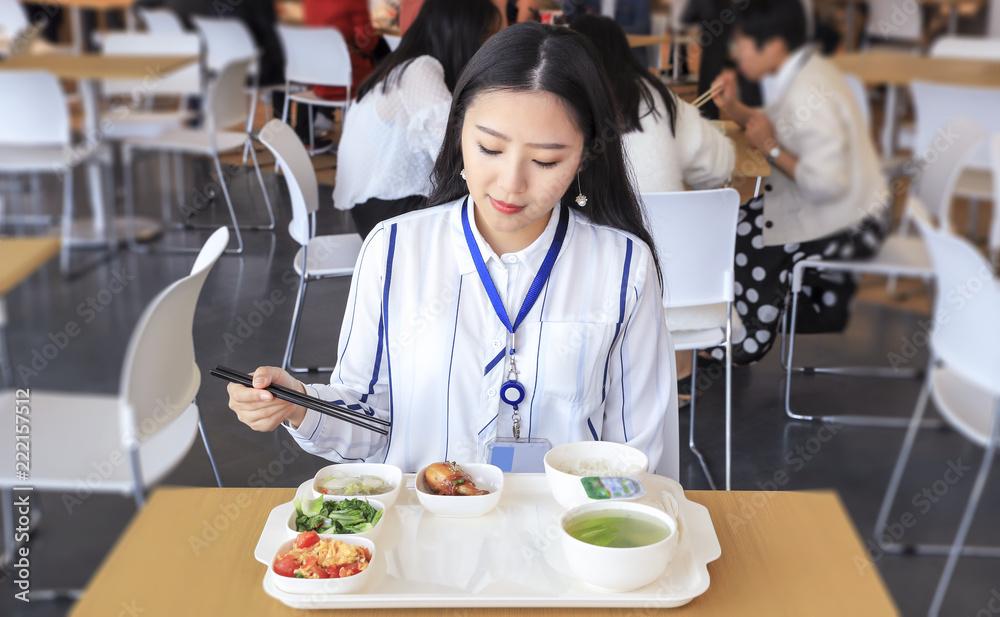 Asian female white-collar worker eating in the cafeteria
