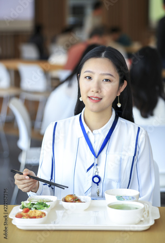 Asian female white-collar worker eating in the cafeteria