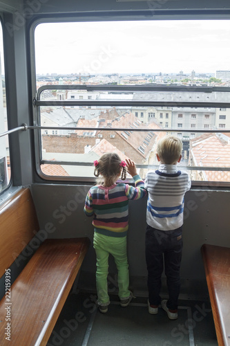 children climb in an empty funicular and look at the panorama of the city of Zagreb