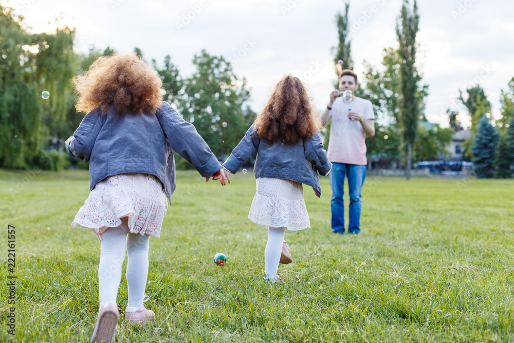Children with parents in the park. Cute family haming fun in nature. Twin toddler sisters holding parents. Happy family concept Children with parents in the park. Cute family haming fun in nature. Twin toddler sisters holding parents. Happy family concept