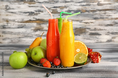 Bottles of tasty smoothies with fruits on wooden table