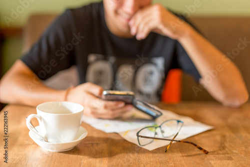 Happy man smiling while looking at cell phone in cafe with coffe