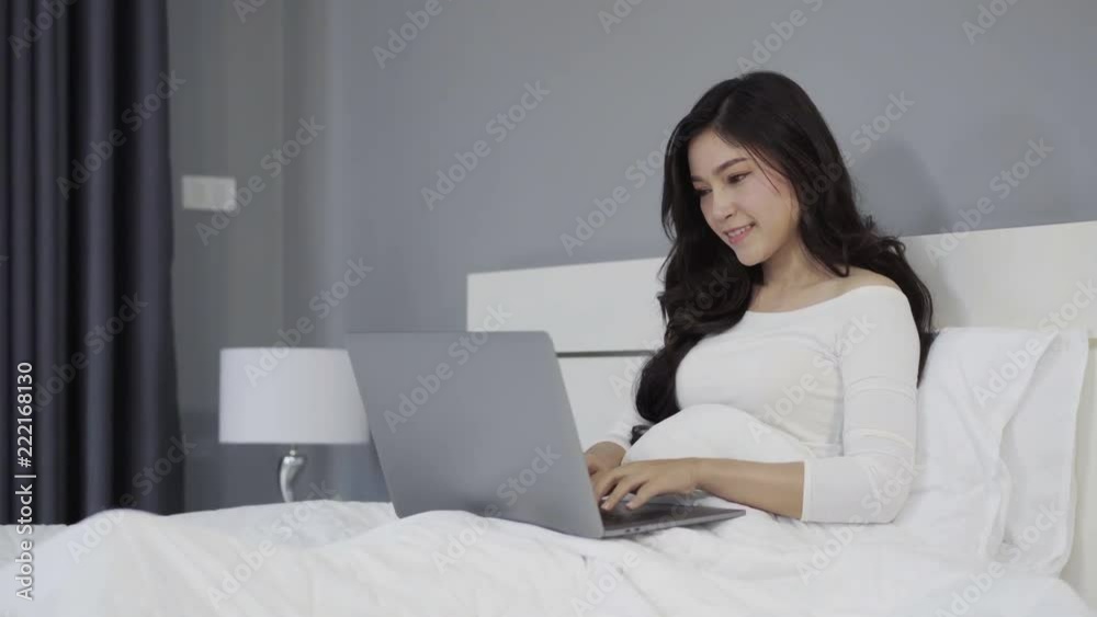 panning shot of woman using a laptop computer on bed panning shot of woman using a laptop computer on bed