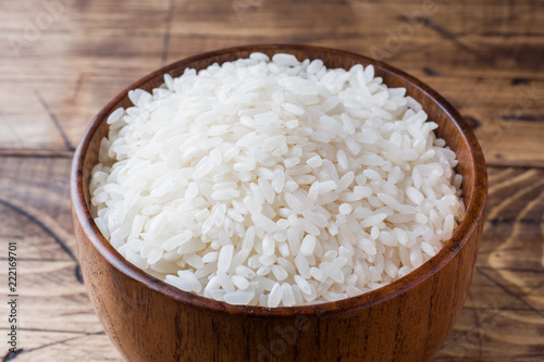 White rice grits in wooden bowl on rustic wooden background.