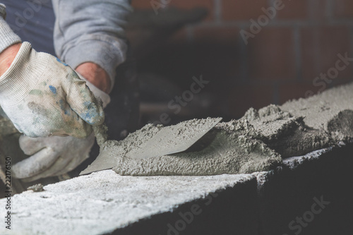 Billede på lærred Real construction worker bricklaying the wall using tools.