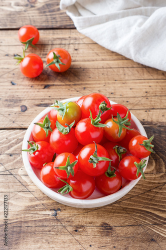 Cherry tomatoes red in ceramic bowl on wooden background