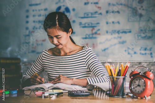 Canvas Print Young student sitting at desk in home studying and reading, doing homework and l