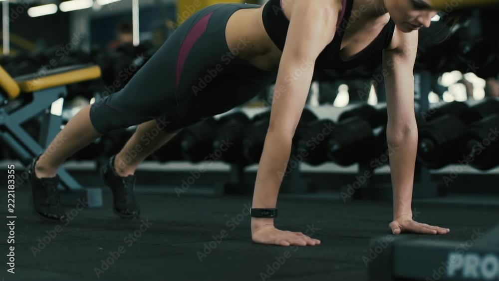 Sportive girl doing plank at gym background Sportive girl doing plank at gym background