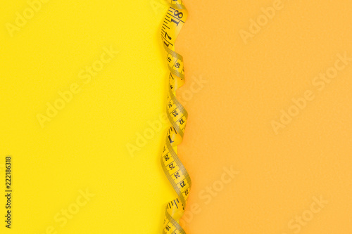 Half yellow half orange background with empty space devided with yellow tape measure photo