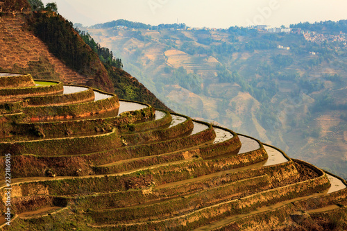 Side View of the Unplanted Rice Terraces in Yuanyang Provence, China, with a Hilltop  Village in the Distance photo