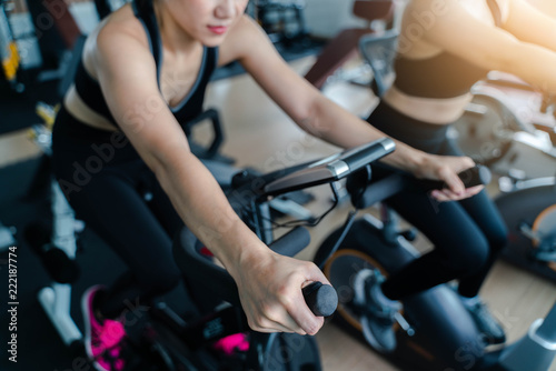 Indoor cycling women doing HIIT cardio workout biking on indoors gym bike