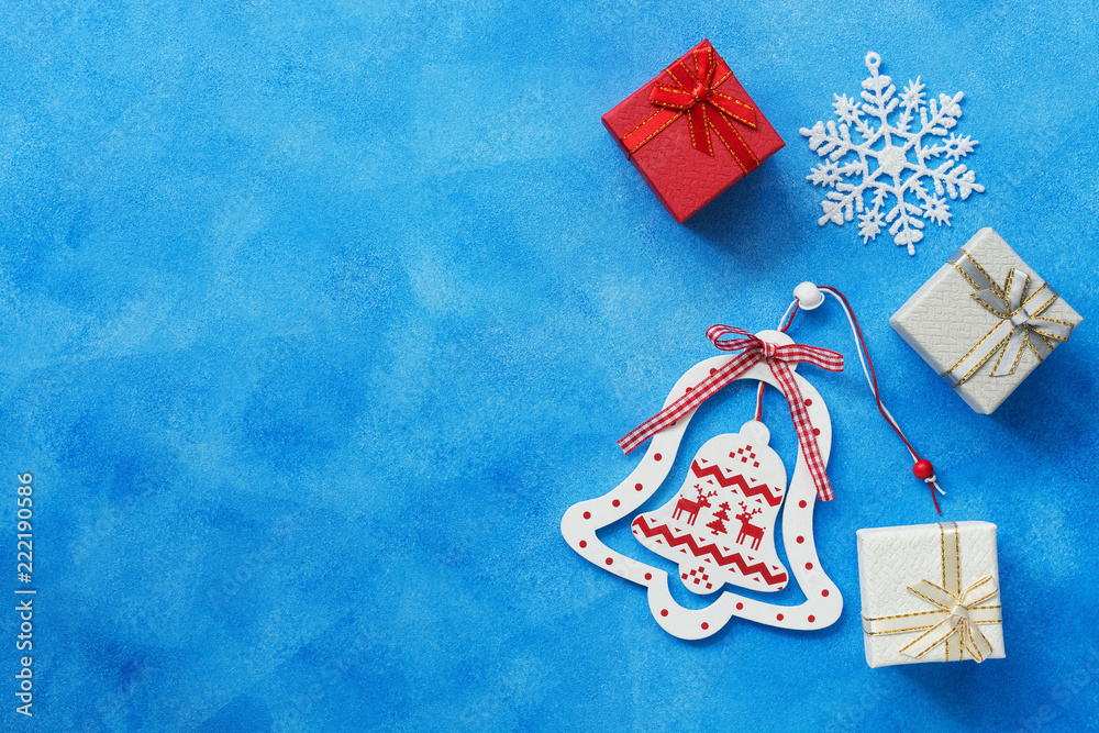 Fototapeta premium Christmas background. Christmas wooden bell, gifts box, snowflake on a blue background. Top view, copy space.