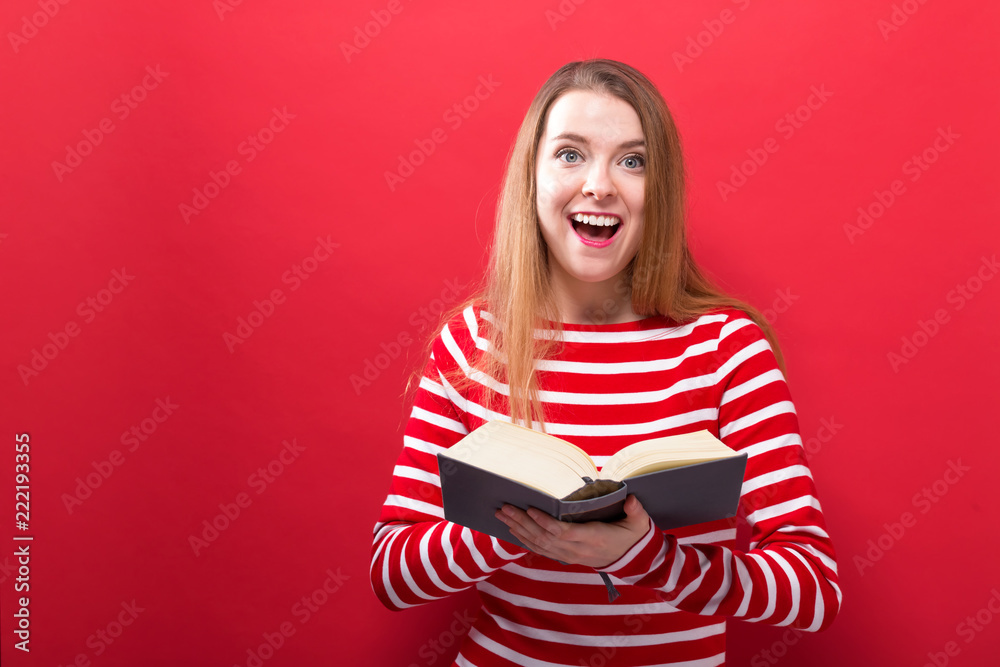 Naklejka premium Young woman with a book on a red background