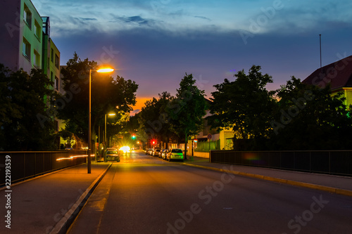 Night shot of a side street with lit lanterns, traffic lights and star-shaped halos