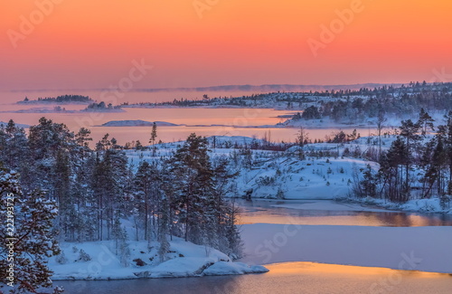 A colorful sunset on the Ladoga lake in the frost. Winter day. Open water hovers from frost. Islands in the snow. © Фёдор Лашков