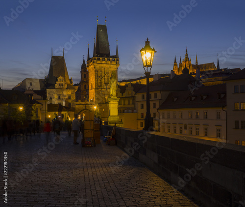 View from Charles Bridge on Mala Strana bridge tower with glowing street lamp nad Prague Castle at night, dark blue sky