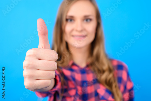 Close up portrait of beautiful delightful satisfied cute woman wearing casual clothes showing thumb-ub symbol isolated on blue background