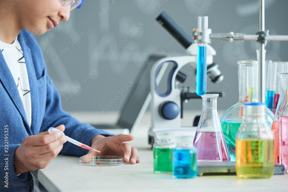 Fototapeta premium High school student putting red substance in petri dish