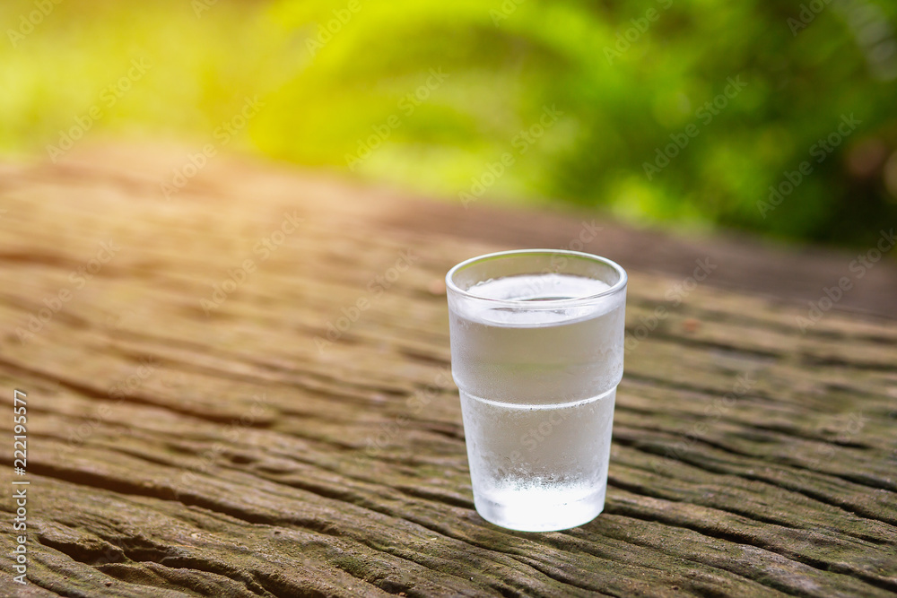 Clean drinking water in clear glass on wooden floor with soft light. Clean drinking water in clear glass on wooden floor with soft light.