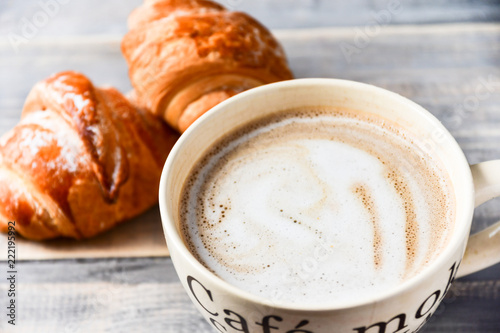 large beige Cup of coffee with milk and croissants on a wooden table. on the Cup inscription in French  top down  mocha coffee  coffee with milk  coffee without sugar 