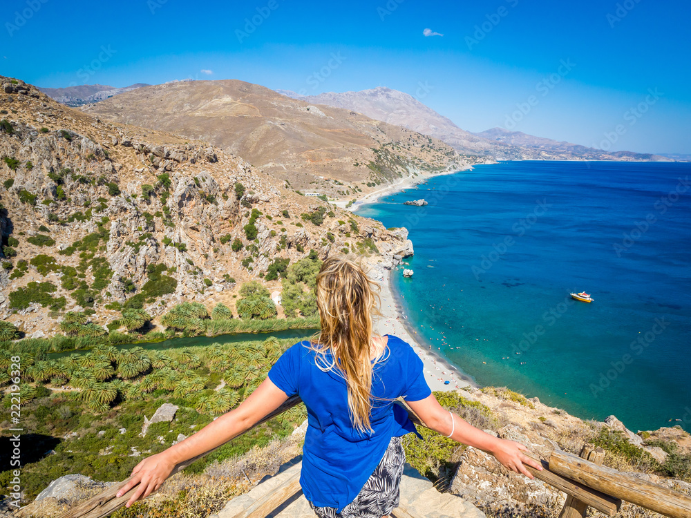 Young beautiful blonde girl contemplates and admires from a high point Preveli Beach (Palm Beach), Crete (Greece)
