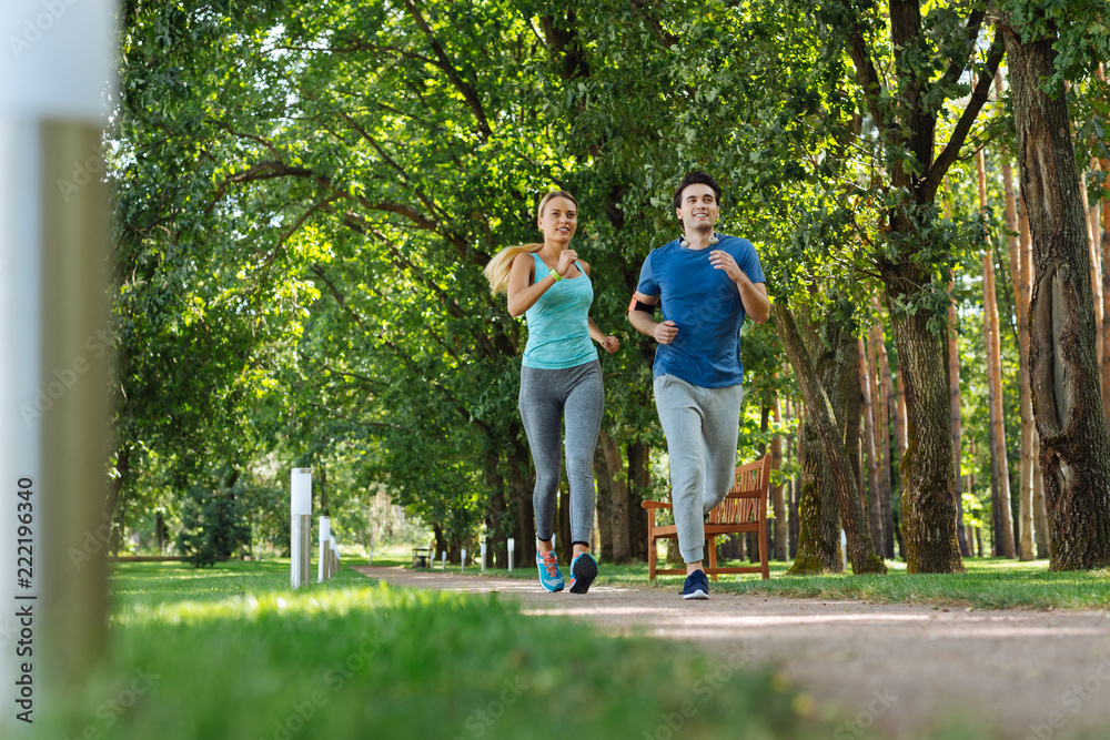 Sport culture. Happy fit couple doing cardio activities while jogging together in the park Sport culture. Happy fit couple doing cardio activities while jogging together in the park
