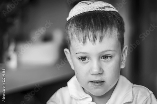 A beautiful Caucasian kid with a traditional Jewish kippah cap on his head. A Russian-speaking Jew in Israel portrait. Post-Soviet Jews make up over 15 per cent of Israeli society. Black and white photo