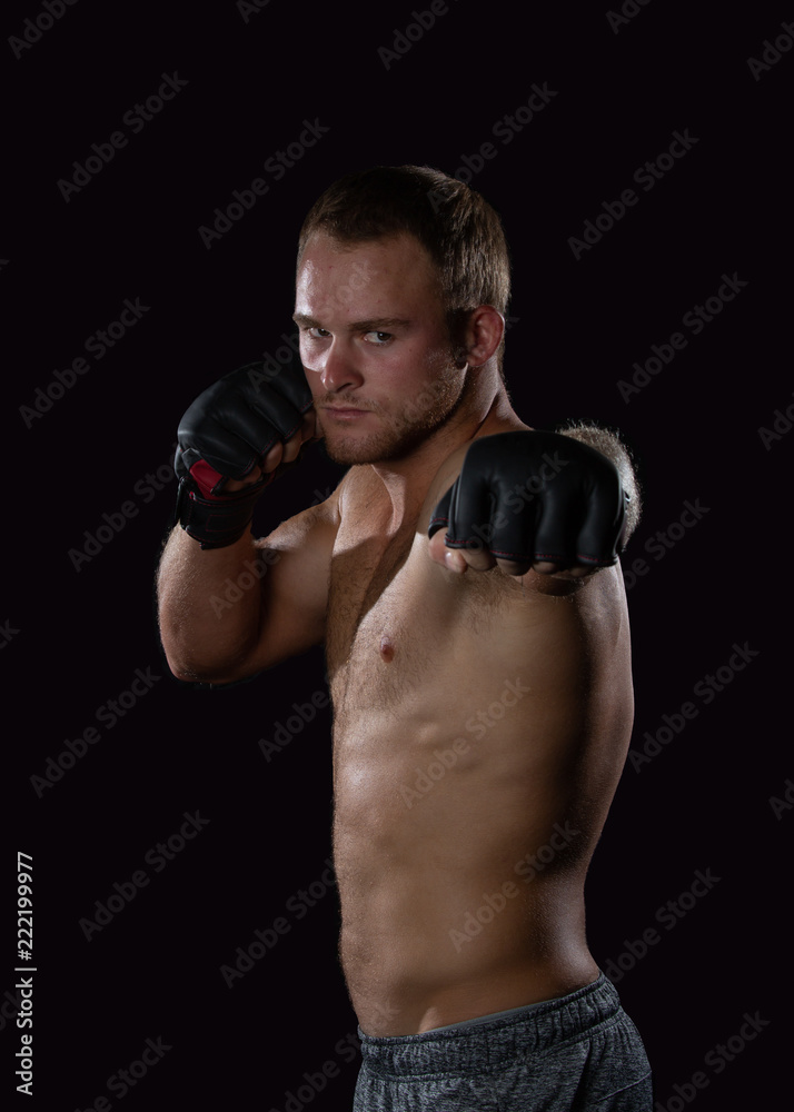 Young well muscled Caucasian adult male wearing mma gloves throwing a left jab