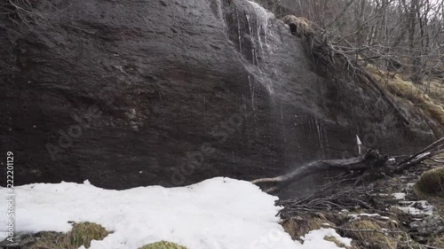 Water coming down onto snow and ice on a waterfall formed by melting snow photo