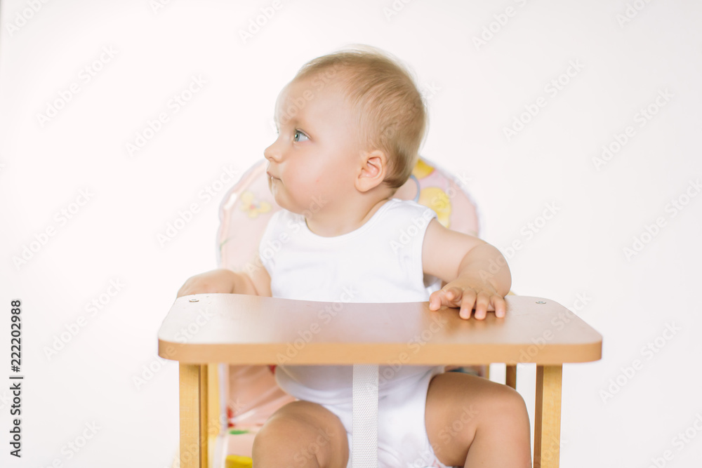 Portrait of a cute little girl smiling while sitting at table, isolated over white Portrait of a cute little girl smiling while sitting at table, isolated over white