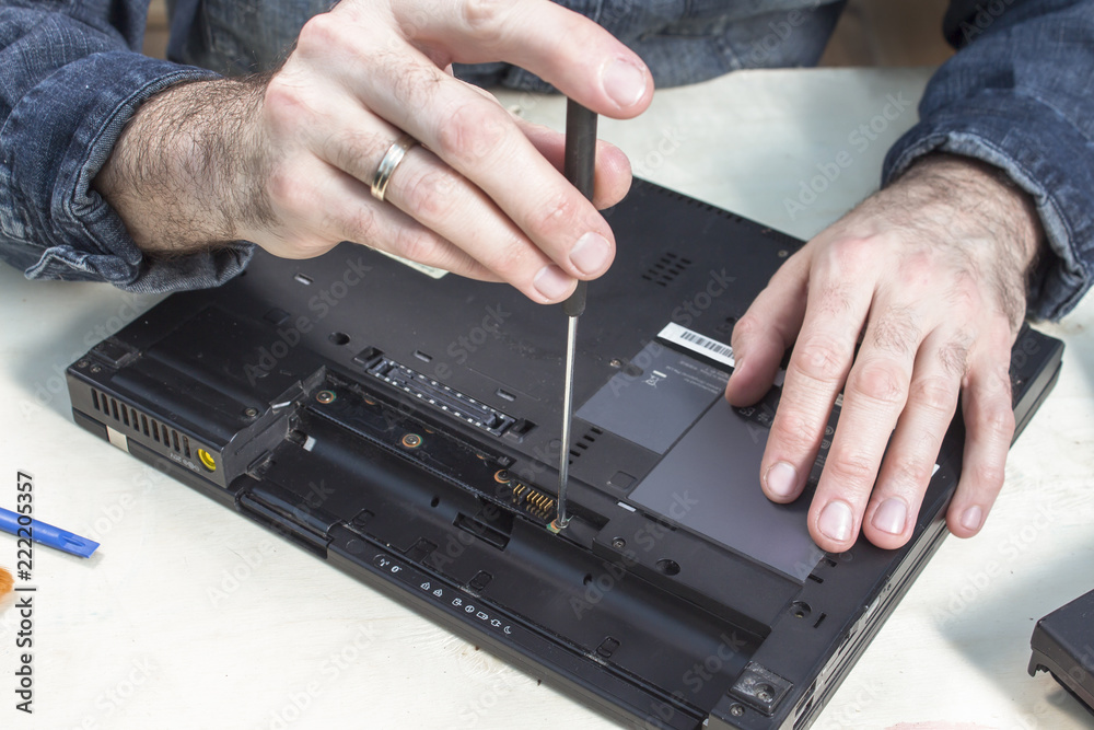 Rozkręcanie obudowy laptopa w serwisie komputerowym.