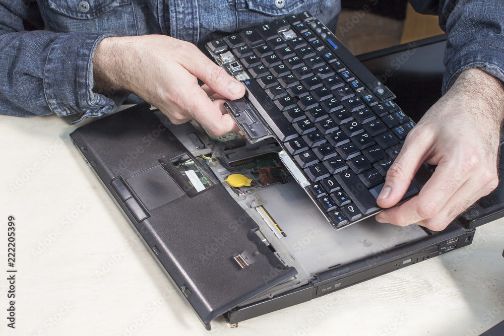 Ręce serwisanta wymieniają zepsutą klawiaturę w laptopie. - obrazy, fototapety, plakaty 