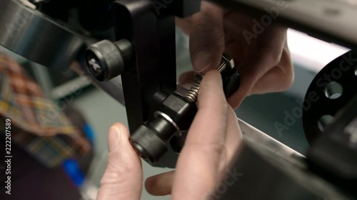 Male hand tightening a clamp around a piece of scaff pole speed rail that forms part of a camera slider dolly system. photo