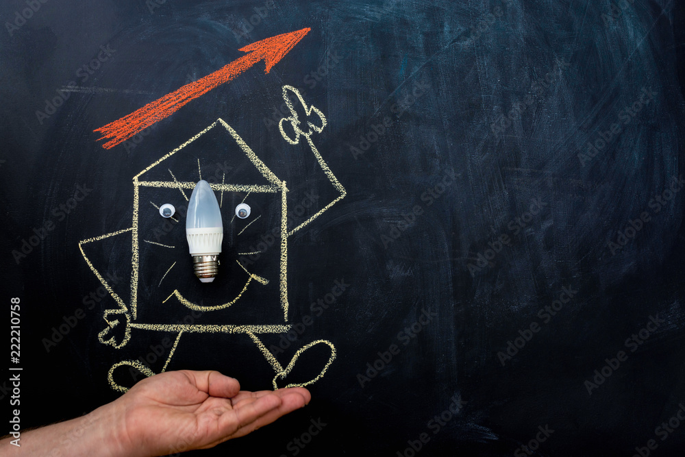 energy saving light bulb and house drawn on chalkboard